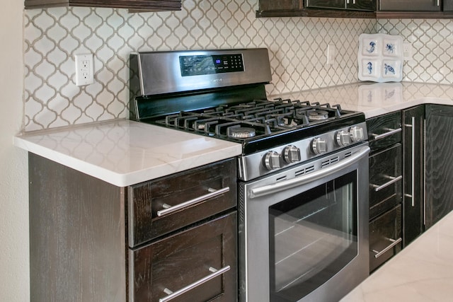 kitchen with tasteful backsplash, light stone counters, stainless steel gas stove, and dark brown cabinets