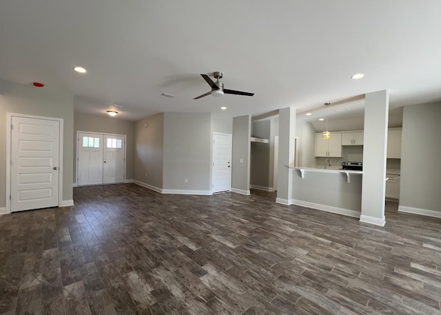 unfurnished living room with dark wood-type flooring, recessed lighting, and baseboards