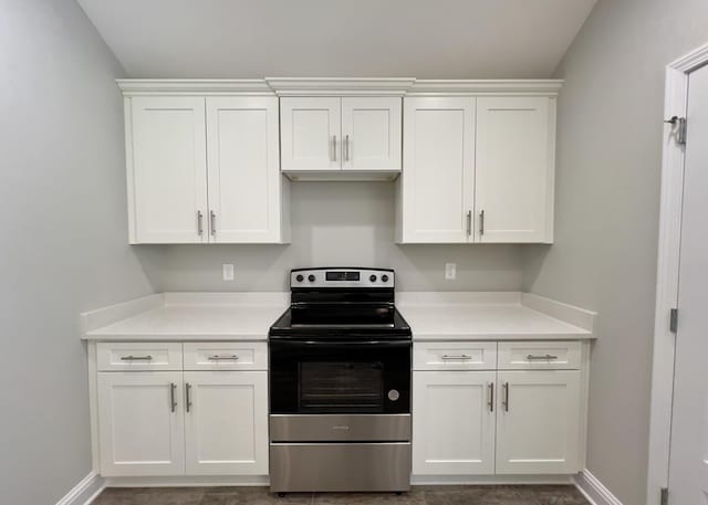 kitchen with electric stove, light countertops, and white cabinets