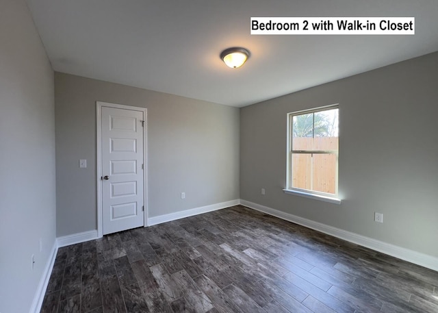 spare room with dark wood-style floors and baseboards