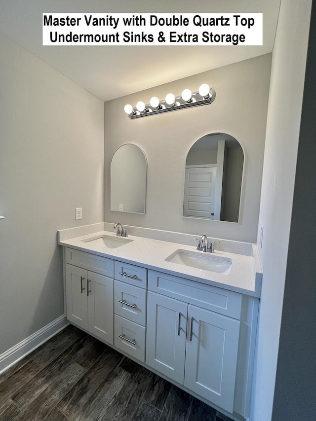 bathroom featuring double vanity, wood finished floors, a sink, and baseboards