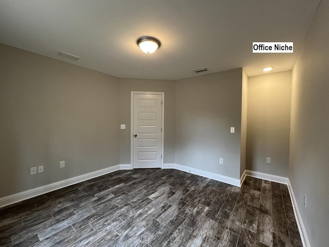 empty room with dark wood-style floors, visible vents, and baseboards