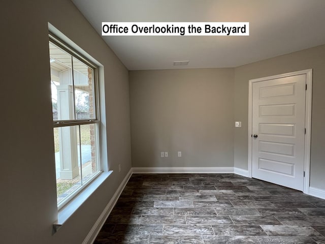 empty room with wood finished floors, visible vents, and baseboards