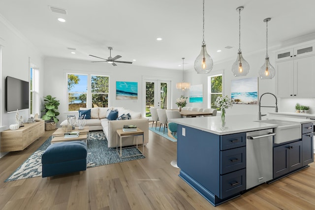 kitchen featuring sink, hanging light fixtures, stainless steel dishwasher, white cabinets, and light wood-type flooring