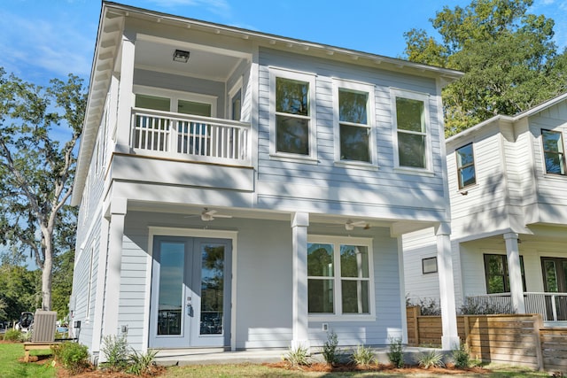 back of property with ceiling fan, a balcony, and french doors