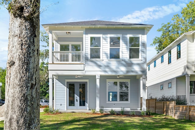 back of property with a yard, french doors, and a balcony