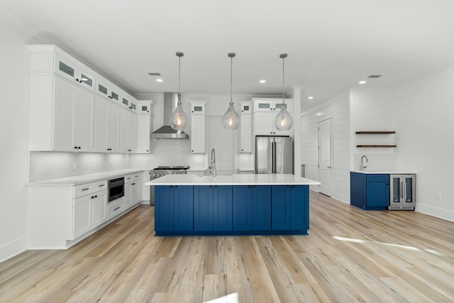 kitchen featuring white cabinets, wall chimney exhaust hood, and appliances with stainless steel finishes