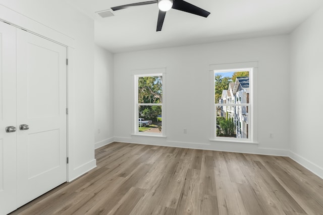 interior space featuring a closet, light hardwood / wood-style flooring, multiple windows, and ceiling fan