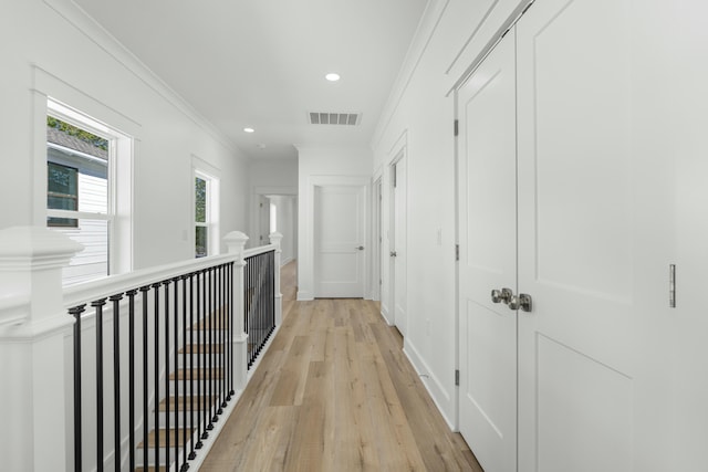 corridor with light wood-type flooring and crown molding