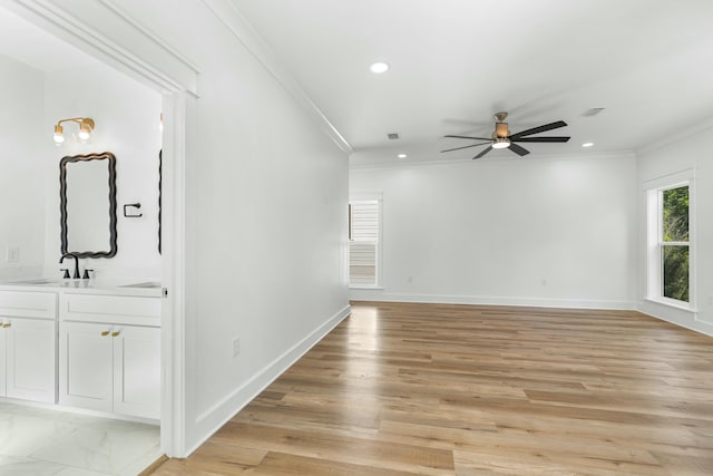 empty room featuring light hardwood / wood-style flooring, ceiling fan, ornamental molding, and sink