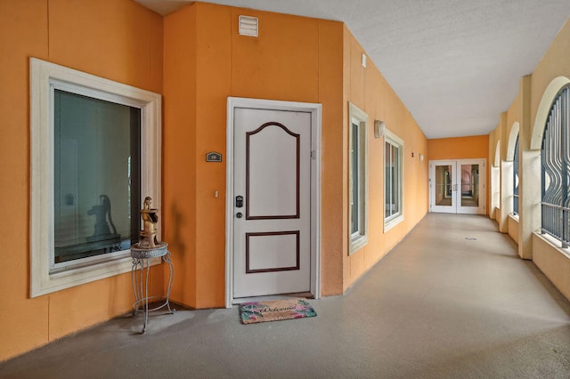 corridor featuring light colored carpet, lofted ceiling, and french doors