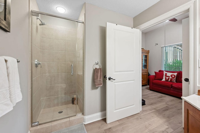 bathroom featuring hardwood / wood-style floors, vanity, an enclosed shower, and a textured ceiling