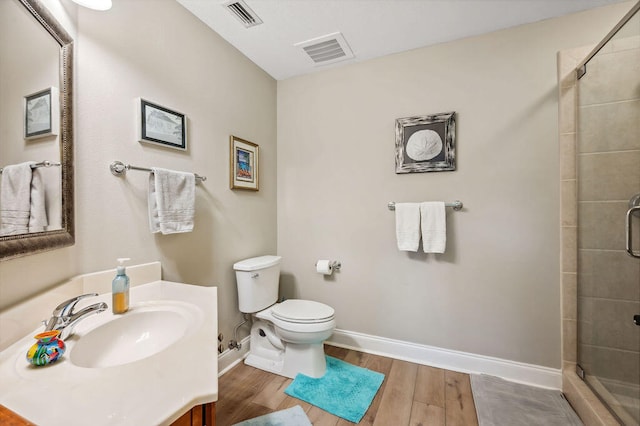 bathroom with vanity, wood-type flooring, a shower with shower door, and toilet