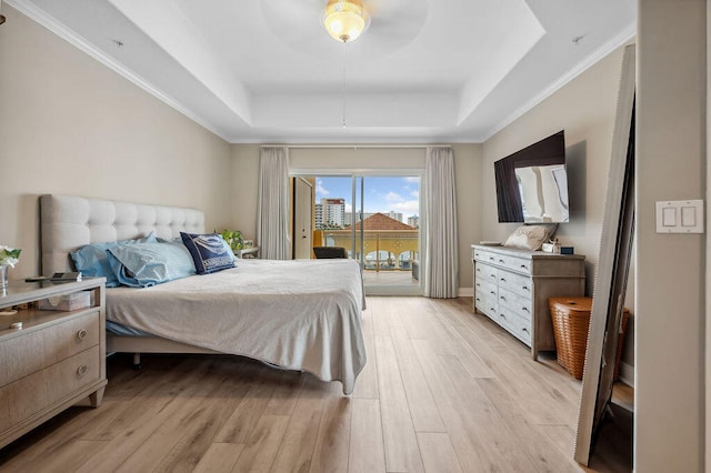 bedroom featuring access to exterior, light hardwood / wood-style floors, a raised ceiling, and crown molding