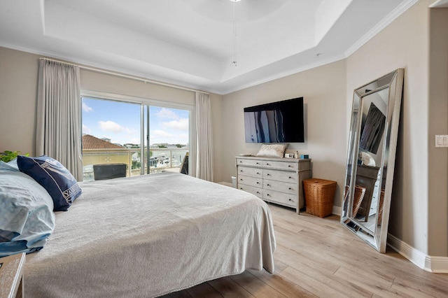 bedroom with ornamental molding, a tray ceiling, and light hardwood / wood-style flooring