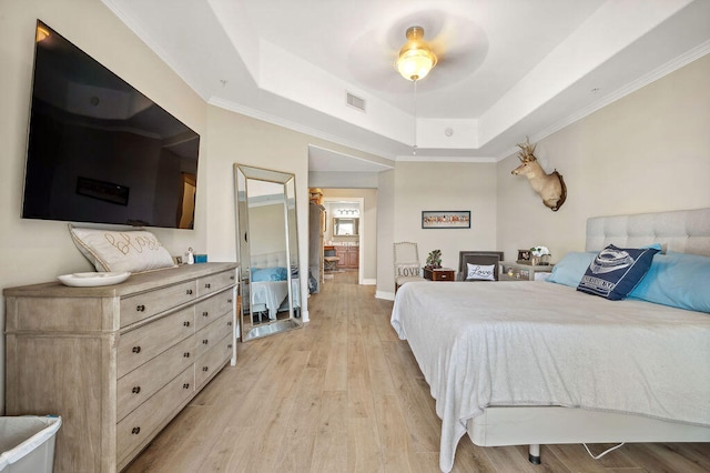 bedroom with ceiling fan, a raised ceiling, light wood-type flooring, and ornamental molding