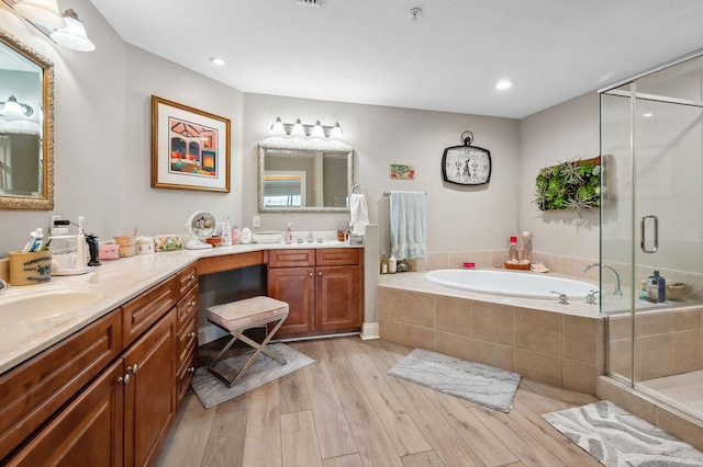 bathroom featuring plus walk in shower, vanity, and hardwood / wood-style flooring