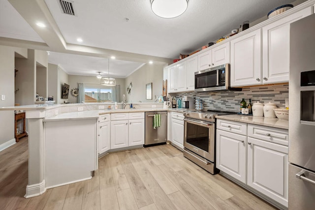 kitchen featuring stainless steel appliances, kitchen peninsula, decorative backsplash, white cabinets, and light wood-type flooring