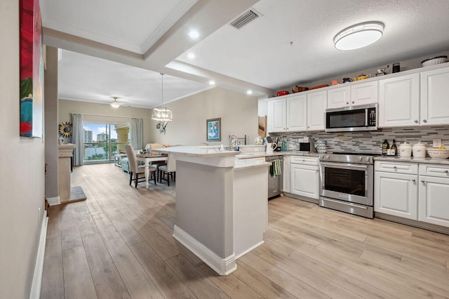 kitchen featuring kitchen peninsula, stainless steel appliances, white cabinetry, and hanging light fixtures