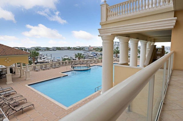 view of pool with a community hot tub, a patio, and a water view