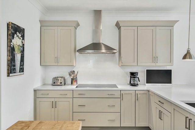 kitchen featuring wall chimney range hood, crown molding, black electric cooktop, tasteful backsplash, and decorative light fixtures