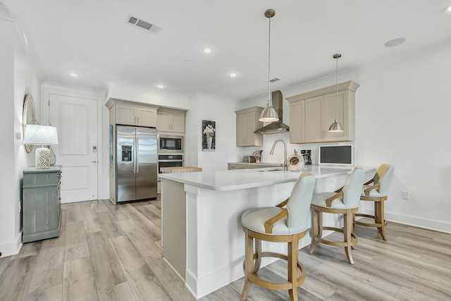 kitchen with wall chimney range hood, a kitchen bar, gray cabinets, appliances with stainless steel finishes, and light wood-type flooring