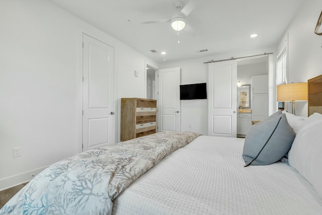 bedroom featuring ceiling fan, a barn door, and ensuite bathroom