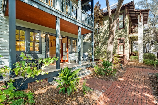 entrance to property featuring a porch and a balcony