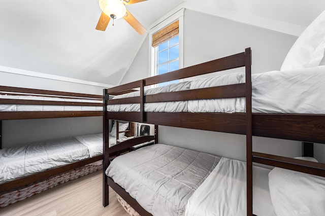 bedroom with ceiling fan, light hardwood / wood-style floors, and vaulted ceiling