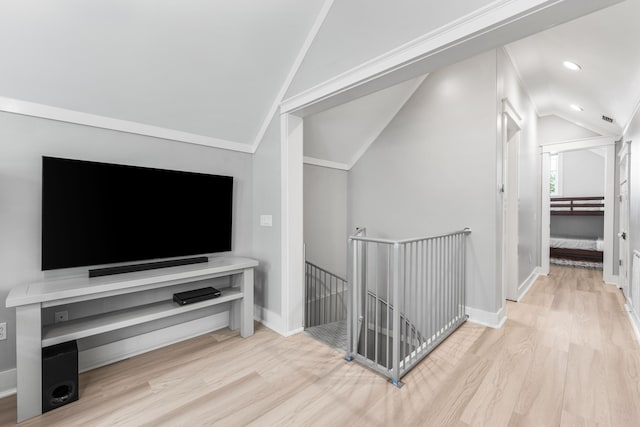 hallway featuring crown molding, lofted ceiling, and light wood-type flooring