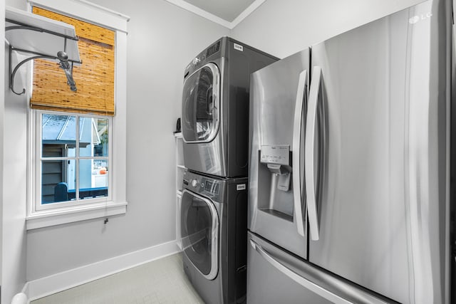 laundry area with light tile patterned floors, stacked washer / dryer, and crown molding