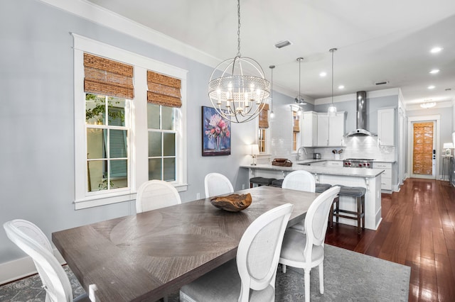 dining area with a chandelier, crown molding, dark wood-type flooring, and sink