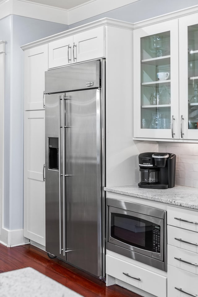 kitchen featuring dark hardwood / wood-style floors, light stone counters, white cabinetry, and appliances with stainless steel finishes