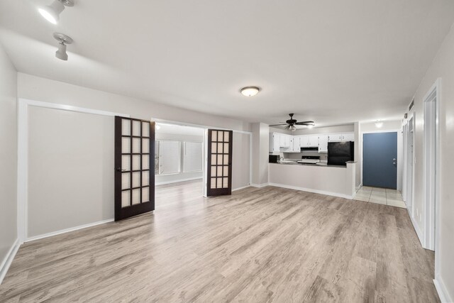 unfurnished living room featuring french doors, light wood-type flooring, and ceiling fan