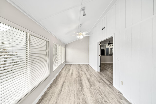 unfurnished living room featuring lofted ceiling, crown molding, wooden walls, ceiling fan, and light wood-type flooring