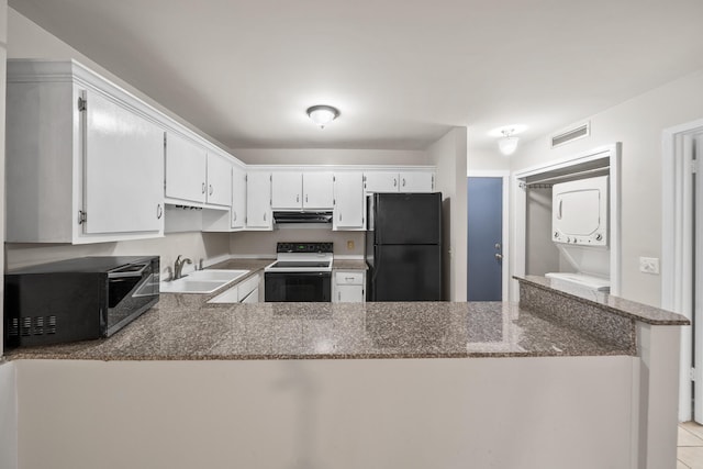 kitchen featuring black refrigerator, kitchen peninsula, sink, white electric stove, and stacked washer and dryer