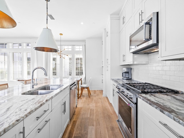 kitchen featuring appliances with stainless steel finishes, white cabinetry, pendant lighting, and sink