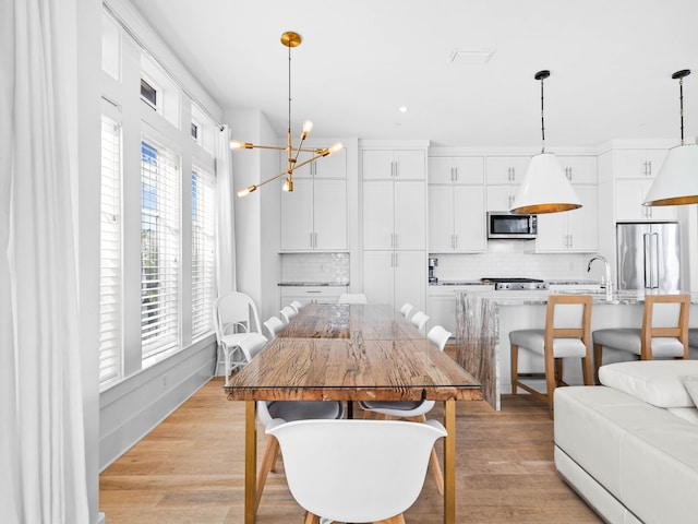 dining area with light wood-type flooring, a wealth of natural light, and a chandelier