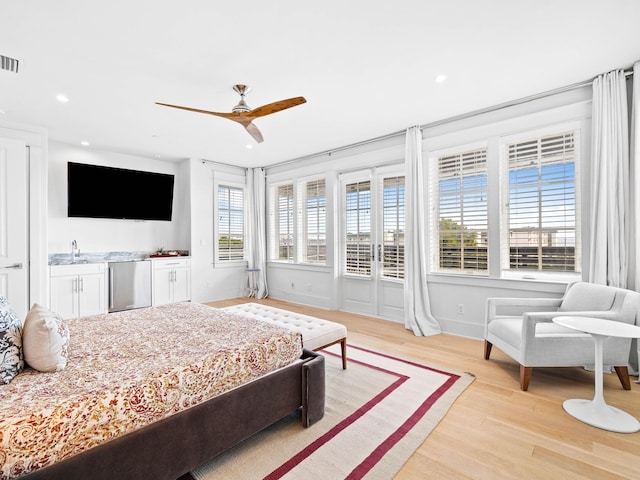 bedroom featuring sink, light wood-type flooring, multiple windows, and ceiling fan