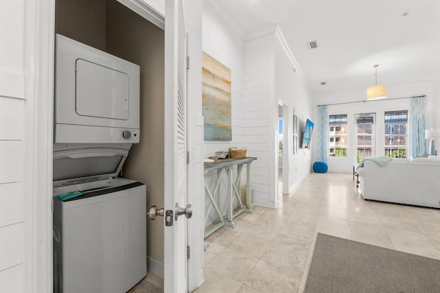 washroom featuring stacked washing maching and dryer, ornamental molding, and light tile patterned floors