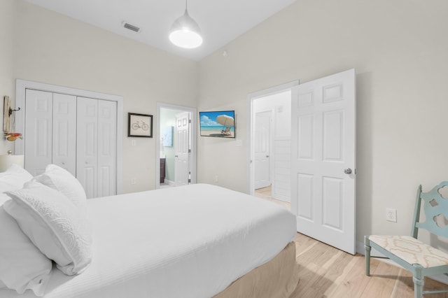 bedroom featuring light wood-type flooring, ensuite bath, and a closet