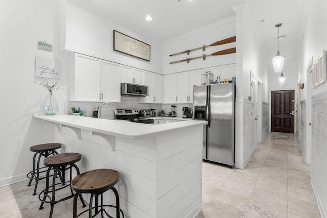 kitchen with white cabinetry, stainless steel appliances, a kitchen breakfast bar, kitchen peninsula, and decorative light fixtures