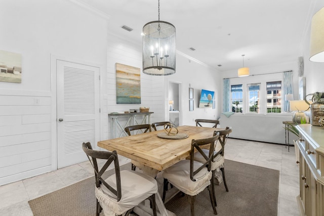 tiled dining room with wooden walls, ornamental molding, and a notable chandelier