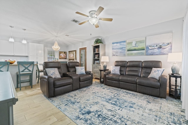 living room with ceiling fan with notable chandelier and light wood-type flooring