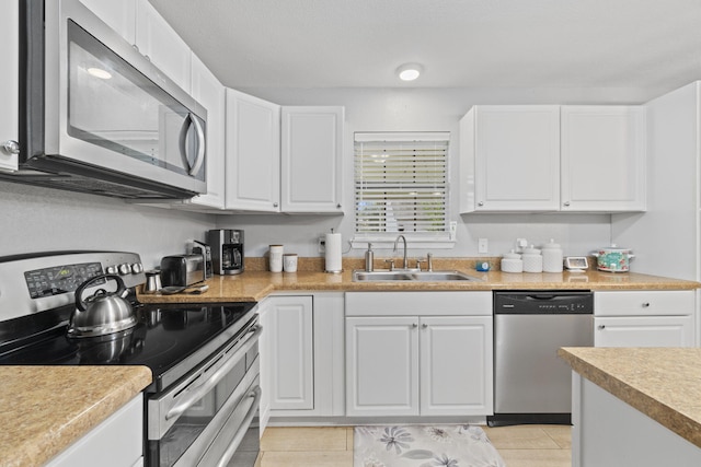 kitchen with white cabinets, light tile patterned floors, stainless steel appliances, and sink