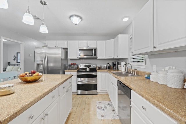 kitchen with sink, white cabinets, light hardwood / wood-style floors, and appliances with stainless steel finishes