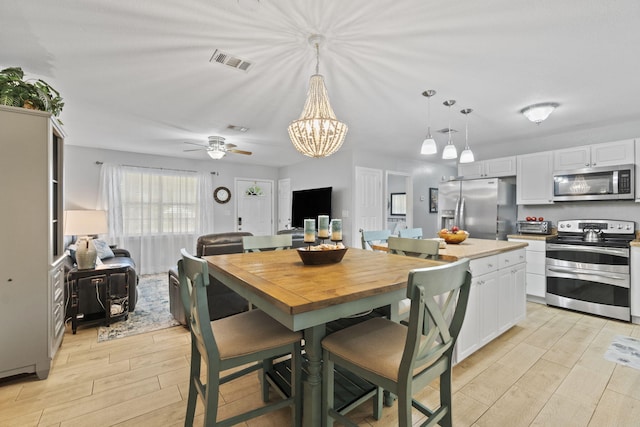 dining area featuring ceiling fan with notable chandelier and light wood-type flooring