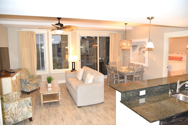 living room with ceiling fan, light wood-type flooring, and sink