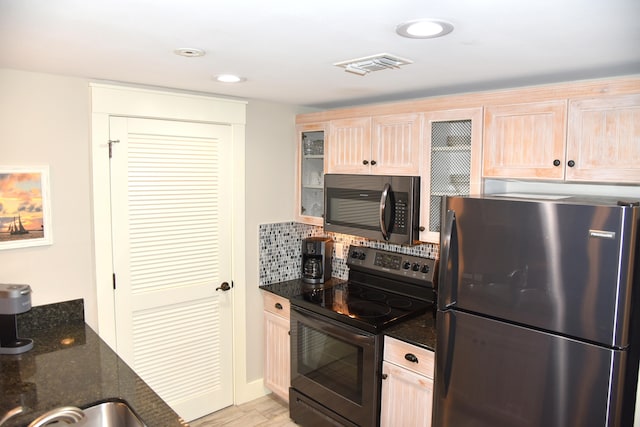 kitchen featuring light brown cabinetry, stainless steel appliances, tasteful backsplash, and dark stone counters