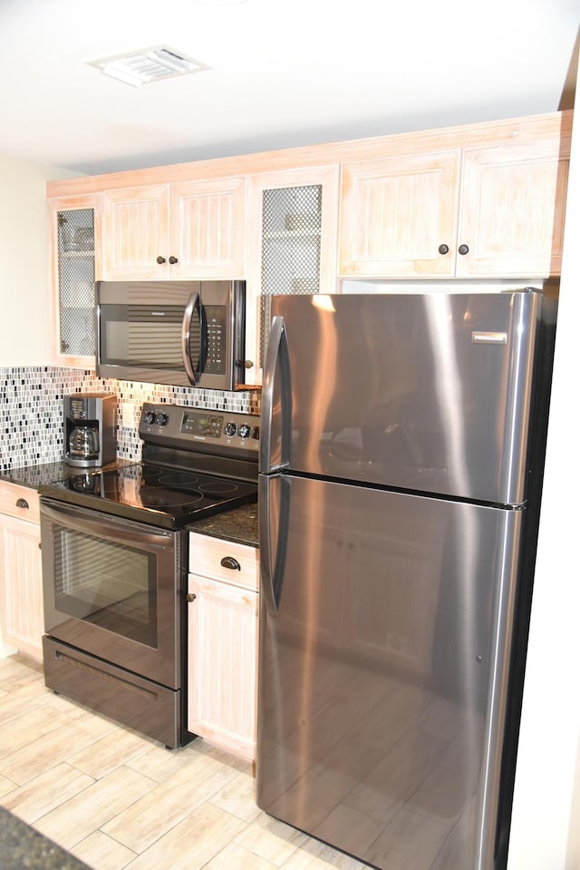9200 Baytowne Wharf Blvd Unit 444/446, Miramar Beach, FL 32550 - kitchen featuring appliances with stainless steel finishes, light brown cabinetry, backsplash, glass insert cabinets, and light wood-style flooring